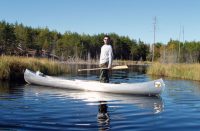 Man standing in canoe on river. A\J AlternativesJournal.ca