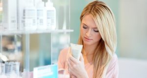 Woman checking the ingredients in beauty products. Alternatives Journal. 