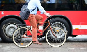 Bicycle commuter riding next to a bus.