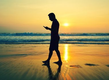 6 Super Summer Apps - man walking on a beach looking at his phone