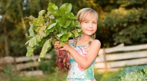 Young girl with root vegetables, learning how food is produced.