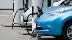 Electric cars being charged at a station. One is blue.