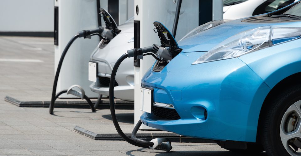 Electric cars being charged at a station. One is blue.