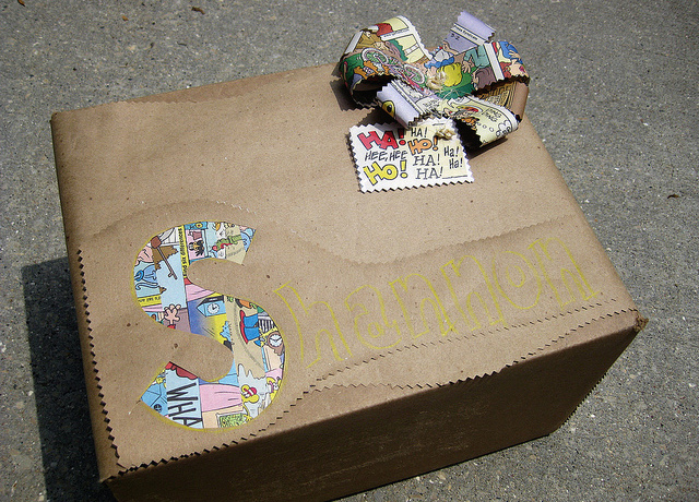 Present wrapped in brown paper with comic bow and cutouts revealing comics underneath.