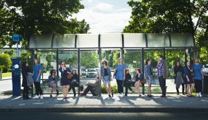 (Photo: a group of people waiting at a bus stop)