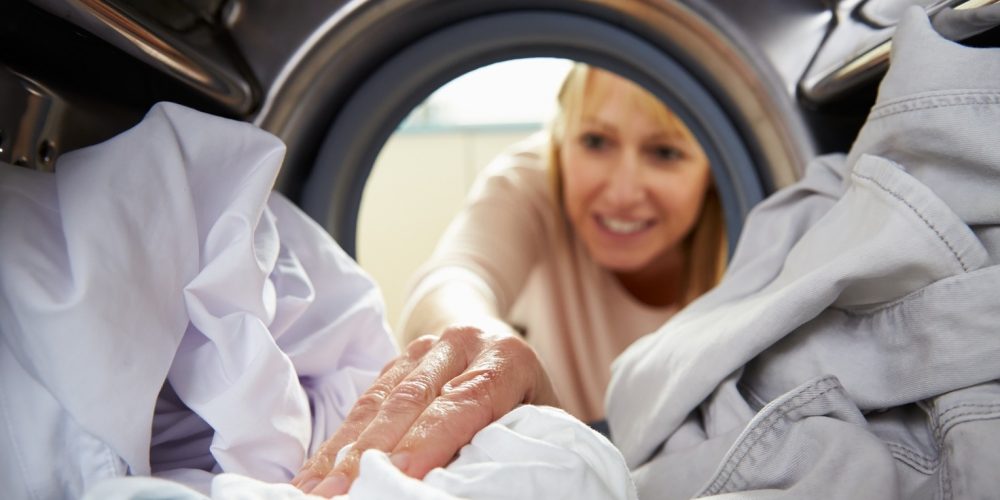 (Photo: a woman reaching into a washing machine)