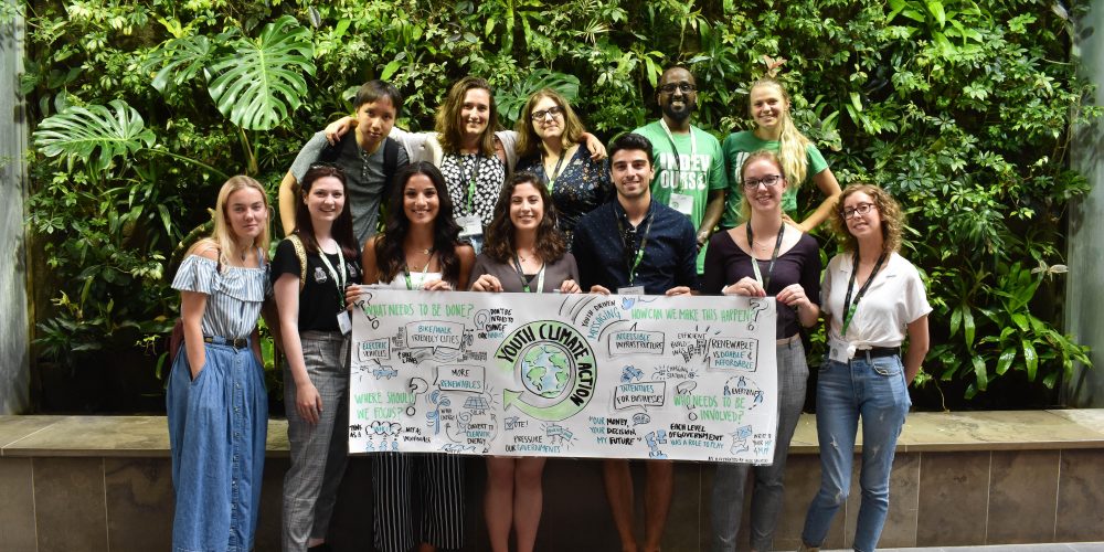 Students holding a YACC sign in front of a green wall