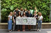 Students holding a YACC sign in front of a green wall